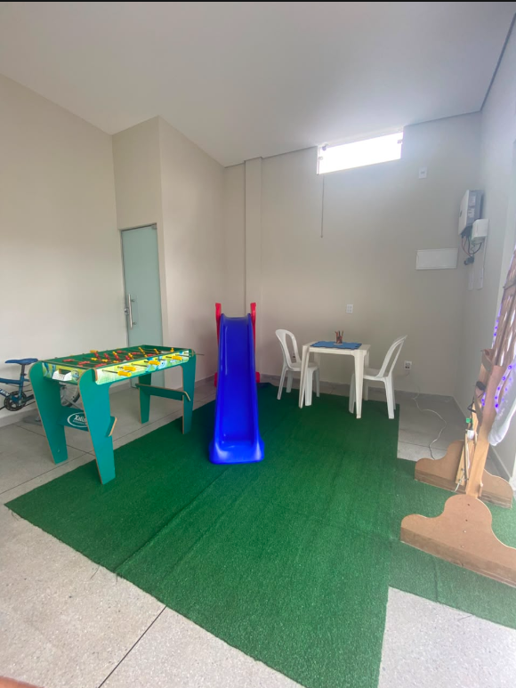 Área recreativa do espaço infantil com escorregador, mesa de jogos e mesa para atividades