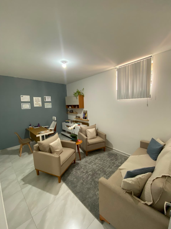Sala de atendimento 1 com poltronas, sofá, mesa de trabalho e decoração acolhedora