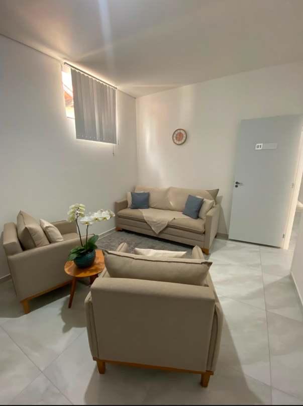 Segundo ângulo da sala de atendimento 1 com conjunto de poltronas e sofá