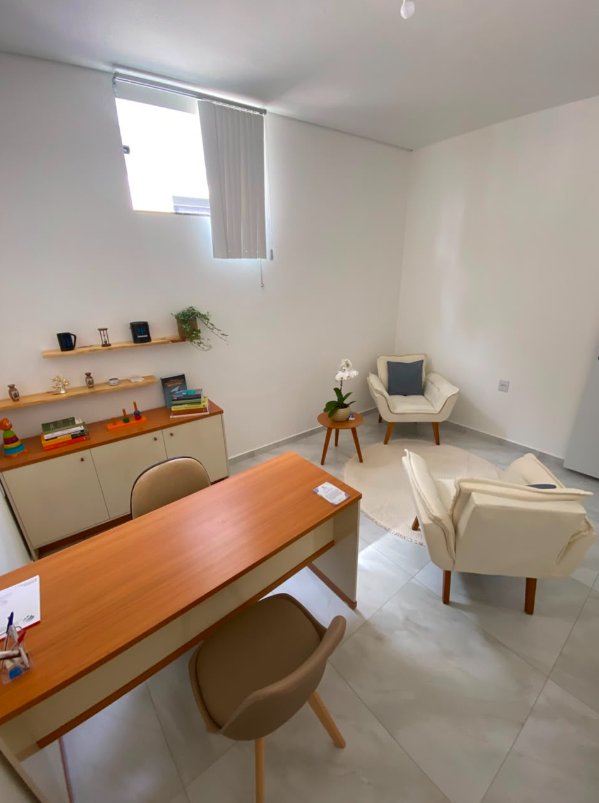 Segundo ângulo da sala de atendimento 2 com mesa de trabalho e poltronas